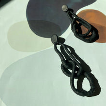 Load image into Gallery viewer, Crafted for bold style, these earrings feature a flexible wire wrapped in soft black leather, creating a unique design. With a long dangle-wrap style, they add drama to any outfit, while remaining lightweight for all-day comfort. The black leather wrapping adds texture and sophistication, offering an edgy yet elegant touch to your look.