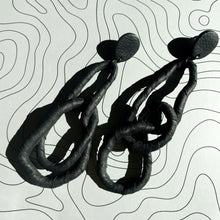 Load image into Gallery viewer, Crafted for bold style, these earrings feature a flexible wire wrapped in soft black leather, creating a unique design. With a long dangle-wrap style, they add drama to any outfit, while remaining lightweight for all-day comfort. The black leather wrapping adds texture and sophistication, offering an edgy yet elegant touch to your look.