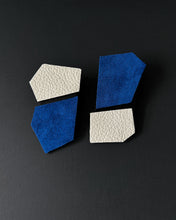 Load image into Gallery viewer, A pair of geometric leather earrings displayed against a black background, showcasing their structured design and contrasting textures, shapes and colours.