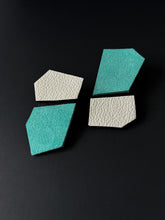 Load image into Gallery viewer, Statement leather earrings in turquoise, black, and white with sharp geometric angles, showcasing their structured design and contrasting textures.