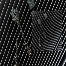 Load image into Gallery viewer, a pair of earrings designed for individuals seeking a unique and edgy accessory. The earrings are mismatched studs made from leather with a geometric shape. One earring features a simple stud design, while the other earring has a longer drop style with two black stainless chains of different lengths adorned with hematite stones.