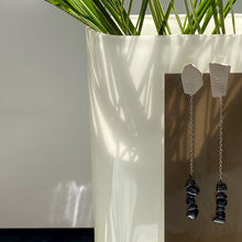 Load image into Gallery viewer, Elevate your style with our contemporary drop earrings. The asymmetrical form and contrasting elements add a modern edge, while luxurious textured leather and hematite provide sophistication and a touch of mystery. Hematite promotes calmness, strength, stability, and protection. With a carefree swing, these earrings allow you to stride tall and restore your equilibrium. Shop now for a statement piece that combines modern elegance with natural healing properties