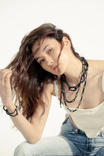 Load image into Gallery viewer, Elevate your jewelry collection with this unique hand-stitched leather chain from WAIWAI. The innovative design features leather links of different lengths and strategically-placed clasps, allowing for multiple styling options. The soft texture and visible grain of the high-quality leather make for a luxurious and comfortable wear. Lightweight and versatile, this chain adds a powerful sense of connectedness to any outfit.