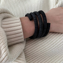 Load image into Gallery viewer, a bracelet made of genuine leather sequins. The bracelet has a helical design that represents evolution, growth, and resilience, echoing the natural world and human cells. It is a statement piece that channels strength and stability. The bracelet is soft, lightweight, and comfortable to wear all day. It can be adjusted to fit your wrist size or stretched out to your desired length.