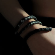 Load image into Gallery viewer, This genuine leather choker/bracelet hybrid lets you express your individuality and set your own standards of fashion. Wear it as a statement piece around your neck or wrist, or create customizable patterns for a unique look every time. Meticulously crafted with genuine leather wrapped around metal wire, this daring accessory is built to last. Be bold, be different, and let the Rebel Coil take your style to the next level.