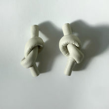 Load image into Gallery viewer, Handcrafted Leather knot stud earrings - a symbol of eternal connection and cherished bond. These earrings offer the perfect amount of visual interest for a flattering and pronounced presence, adding simple sophistication whether you're dressed up or down. The luxurious feel and suppleness of the fine leather is something to be admired, and the subtle colour-matched stitching reveals impeccable hand craftsmanship. Feel anchored with the knot and enjoy the timeless elegance of these earrings.