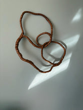 Load image into Gallery viewer, Handmade brown leather wall sculpture with flowing organic circular lines mounted on white wall.