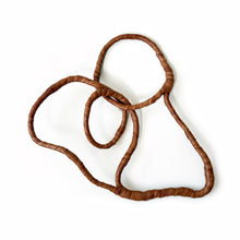 Load image into Gallery viewer, Handmade brown leather wall sculpture with flowing organic circular lines mounted on white wall.