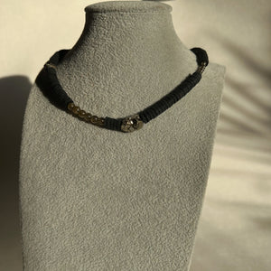 Handcrafted necklace featuring black leather discs, labradorite stones with iridescent sheen, and metallic pyrite gemstones, designed with a bold and modern aesthetic.