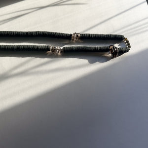 Handcrafted necklace featuring black leather discs, glossy obsidian stones, and translucent smoky quartz gemstones, designed with a bold and modern aesthetic.