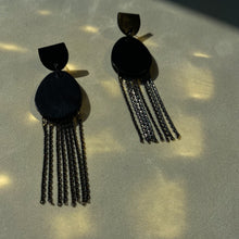 Load image into Gallery viewer, Discover our &#39;Affinity&#39; Black Leather Earrings. These earrings combine sleek black leather in a stud-style semicircle and an elongated oval pendant adorned with delicate chains. The design balances modern allure and timeless charm. Perfect for formal occasions or adding a touch of noir luxury. Lightweight and elegant, these earrings embody sophistication in motion
