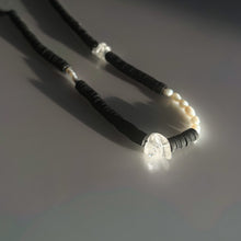 Load image into Gallery viewer, Handcrafted necklace featuring black leather discs, freshwater pearls, and clear quartz gemstones, designed with a modern, tactile aesthetic.