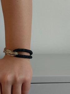 Hand wearing two bracelets on a neutral background
