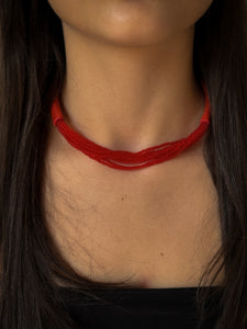 A choker that pairs hand-stitched leather with cascading strands of glass beads. The tubular leather form gives it presence, while the beads add fluid movement in a striking red. Lightweight and adjustable, made for moments that stand out.