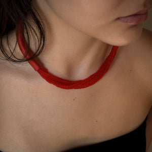 A choker that pairs hand-stitched leather with cascading strands of glass beads. The tubular leather form gives it presence, while the beads add fluid movement in a striking red. Lightweight and adjustable, made for moments that stand out.