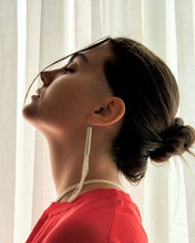 Load image into Gallery viewer, Woman with a bun and red top against a white curtain background wearing long beaded leather earrings