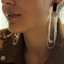 Load image into Gallery viewer, Close-up of a person wearing a dangling leather glass bead earring with a blurred background