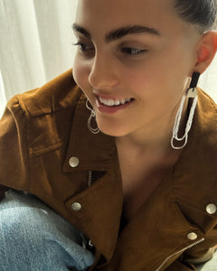 Close-up of a person wearing a dangling leather glass bead earring with a blurred background