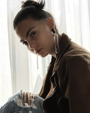Load image into Gallery viewer, Person wearing a brown jacket and ripped jeans sitting in front of white curtains wearing a dangling leather glass bead earring 