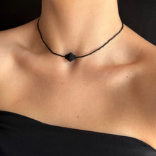 Load image into Gallery viewer, Person wearing a black beaded necklace against a dark background