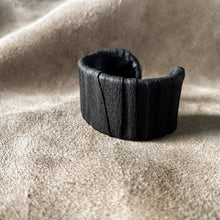 Load image into Gallery viewer, A handcrafted black leather cuff bracelet featuring a ridged texture and a minimal design