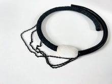 Load image into Gallery viewer, A handcrafted choker featuring a smooth white jade stone, stainless steel chains draping elegantly, a hand-stitched leather tube on one side, and individually hand-punched leather discs on the other. This bold and modern design combines texture and craftsmanship for a striking statement piece.