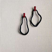 Load image into Gallery viewer, A pair of reshapable earrings handcrafted from black leather with a textured finish, forming irregular looped shapes, accented by bold red leather connectors. Lightweight and versatile for unique styling.