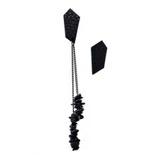 Load image into Gallery viewer, a pair of earrings designed for individuals seeking a unique and edgy accessory. The earrings are mismatched studs made from leather with a geometric shape. One earring features a simple stud design, while the other earring has a longer drop style with two black stainless chains of different lengths adorned with hematite stones.