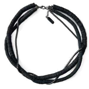 Three-layer elegant leather necklace featuring one strand of gleaming hematite beads and two strands of hand-cut black leather beads in varying sizes, emphasizing a sophisticated and mysterious appearance.