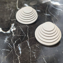 Load image into Gallery viewer, A pair of taupe layered leather earrings with concentric circular designs, handcrafted for a bold and dimensional look.