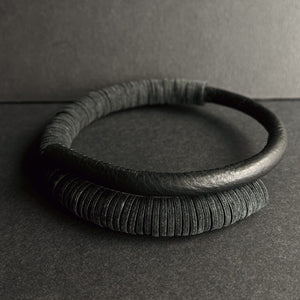 A close-up image of a Texture Fusion Leather Choker featuring a blend of leather textures, smooth hand-stitched tube and punched leather disks displayed against a neutral background