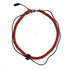Close-up of red leather disk choker with hand-stitched black leather tube and thin black glass bead string worn on neck