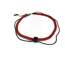 Load image into Gallery viewer, Close-up of red leather disk choker with hand-stitched black leather tube and thin black glass bead string worn on neck