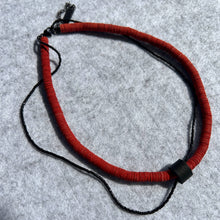 Load image into Gallery viewer, Close-up of red leather disk choker with hand-stitched black leather tube and thin black glass bead string worn on neck