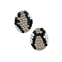 Load image into Gallery viewer, Close-up of snake-inspired earrings made from black, beige, and white leather. The layered design resembles scales, featuring a bold mosaic pattern with a textured, modern look. Handcrafted from upcycled leather, they are lightweight and sustainable.