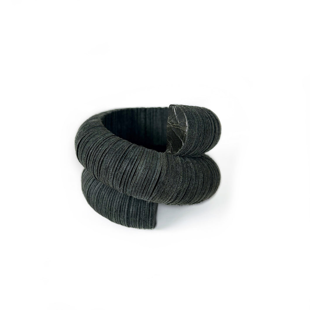 Handcrafted bracelet made from upcycled leather in a rich green tone, featuring a sculptural and layered design with a unique spiral form.