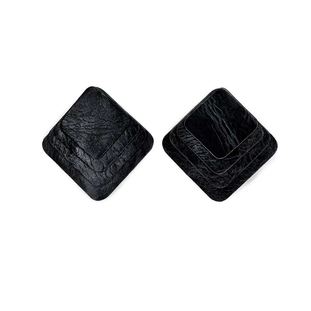 Square black leather earrings with rounded corners, featuring layered leather design for a dimensional and sculptural look.