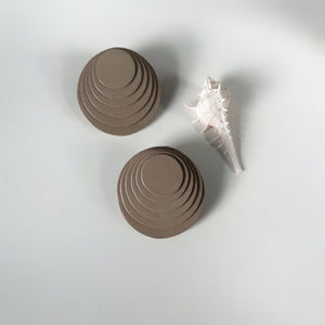 A pair of taupe layered leather earrings with concentric circular designs, handcrafted for a bold and dimensional look.