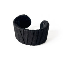 Load image into Gallery viewer, A handcrafted black leather cuff bracelet featuring a ridged texture and a minimal design