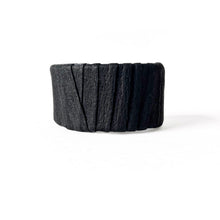 Load image into Gallery viewer, A handcrafted black leather cuff bracelet featuring a ridged texture and a minimal design