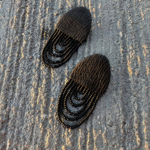 Black leather earrings with cascading shiny bead layers, featuring a textured finish and lightweight, modern design.