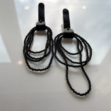 Load image into Gallery viewer, Pair of Noir Cascade earrings featuring black Japanese glass beads cascading in layered strands, combined with soft black leather accents for a bold and elegant look.