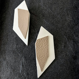 Handcrafted leather earrings featuring oversized geometric sharp shapes in beige over white. The confident, stylish design and dramatic oversized flair complement any outfit with a sleek and contemporary aesthetic.