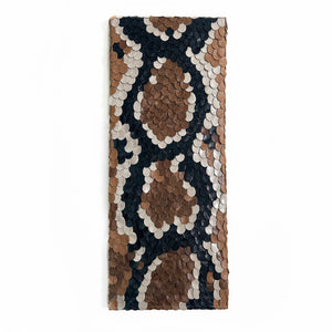 Handcrafted wall art made from upcycled leather, featuring a snakeskin-inspired design with individually hand-punched scales in earthy tones, perfect for adding texture and sustainability to modern interiors.