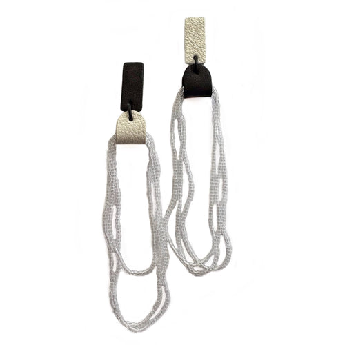 Mismatched earrings combining black and white leather tops with cascading strands of transparent glass beads.