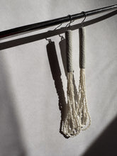 Load image into Gallery viewer, A pair of handcrafted earrings with ivory leather cylindrical tops, cascading strands of white glass seed beads, and hypoallergenic stainless steel hooks.