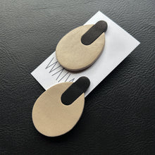 Load image into Gallery viewer, Minimalist leather earrings in soft beige and black, featuring a modern, oval shape with a sleek, layered design. Lightweight and sustainably crafted for an effortless, sophisticated look.