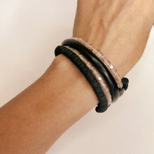 Load image into Gallery viewer, Black leather coil bracelet made from punched disks and stitched leather tube, with blush pink shiny glass beads