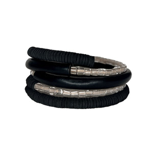 Black leather coil bracelet made from punched disks and stitched leather tube, with blush pink shiny glass beads

