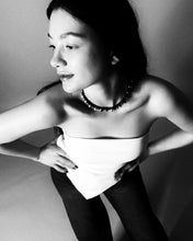 Load image into Gallery viewer, Black and white portrait of a woman wearing a strapless top and dark pants.